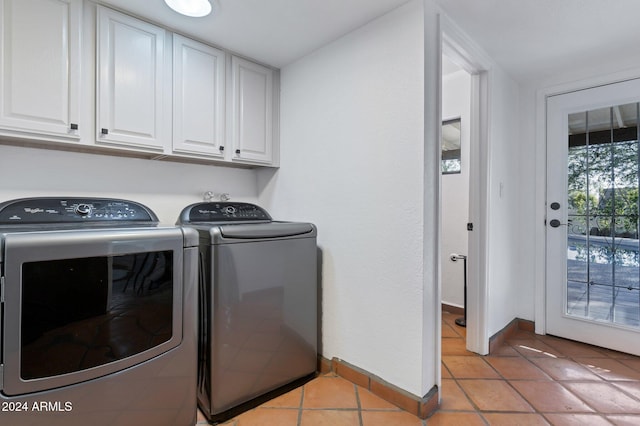 washroom featuring cabinets, light tile patterned floors, and washing machine and clothes dryer