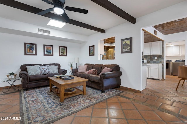 tiled living room featuring ceiling fan, beamed ceiling, and washer and dryer