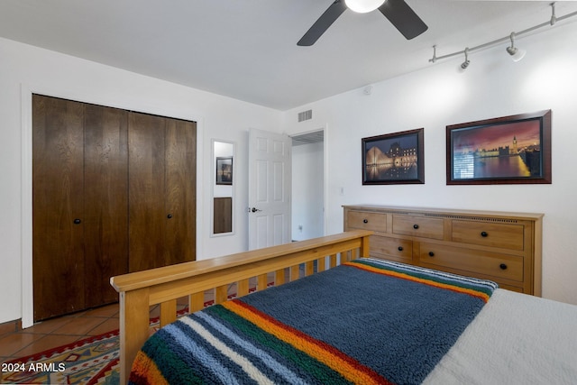 tiled bedroom featuring ceiling fan, a closet, and rail lighting