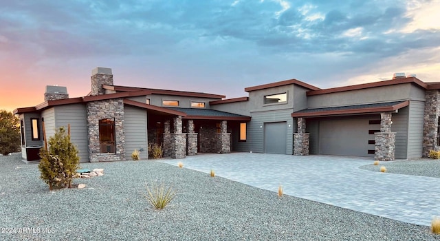 view of front of property featuring a garage, stone siding, decorative driveway, and a chimney