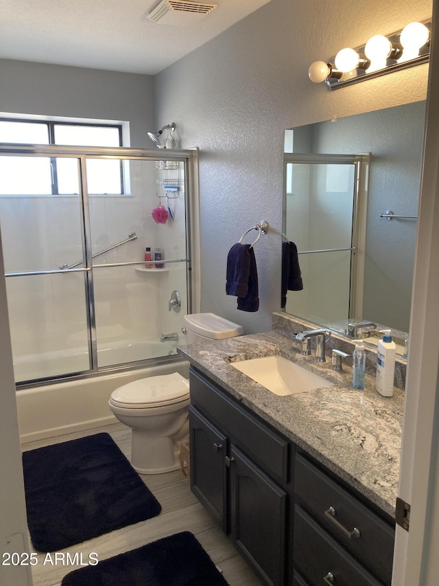 full bathroom featuring toilet, vanity, and shower / bath combination with glass door