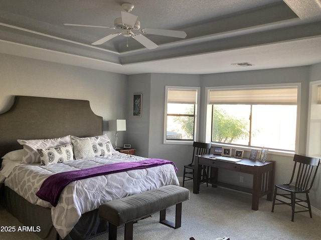 carpeted bedroom featuring ceiling fan and a tray ceiling