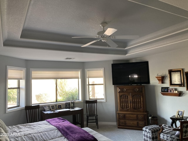 bedroom with ceiling fan, a tray ceiling, carpet floors, and a textured ceiling