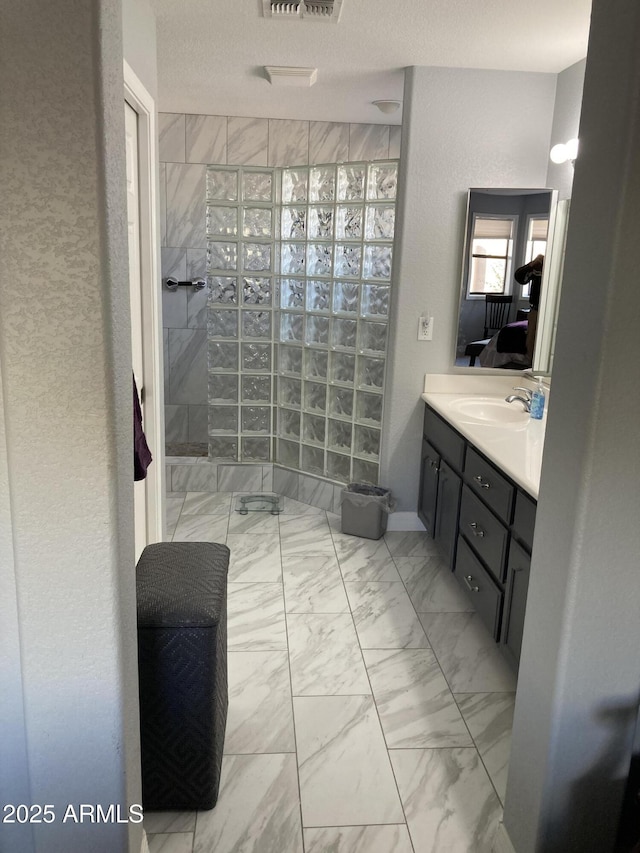 bathroom with a tile shower and vanity