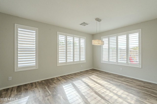 spare room featuring visible vents, baseboards, and wood finished floors