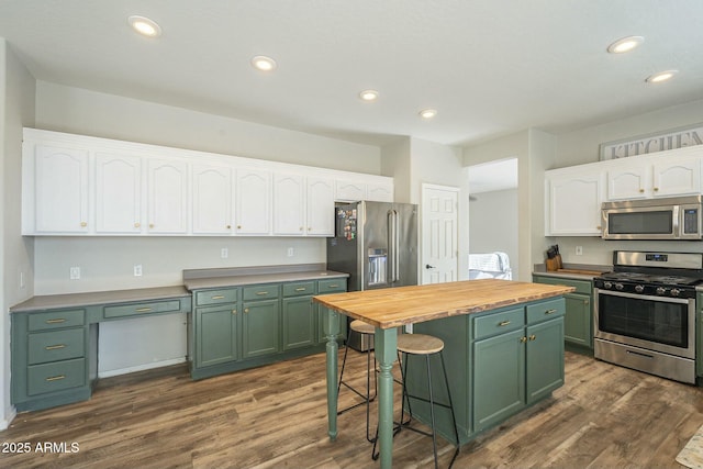 kitchen featuring white cabinetry, stainless steel appliances, wood counters, and green cabinetry