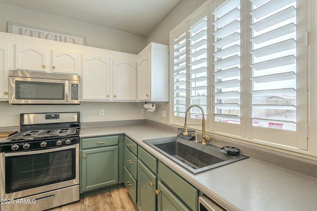 kitchen featuring a sink, white cabinetry, stainless steel appliances, green cabinets, and light countertops