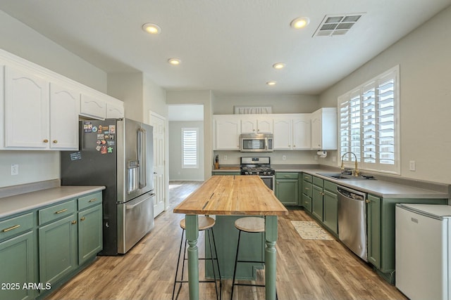 kitchen featuring visible vents, a sink, white cabinetry, appliances with stainless steel finishes, and green cabinetry