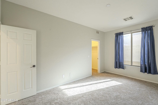 carpeted spare room with visible vents and baseboards