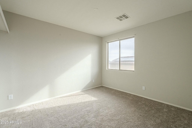 spare room featuring baseboards, visible vents, and carpet floors