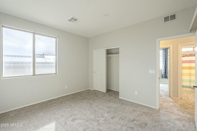 unfurnished bedroom with visible vents, light colored carpet, and multiple windows