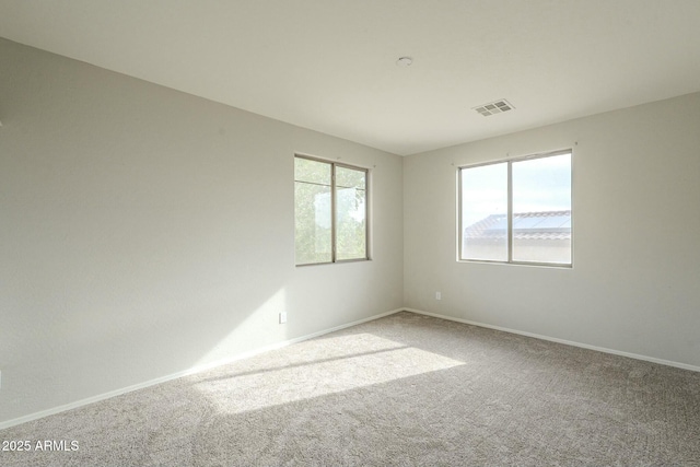 unfurnished room with visible vents, a healthy amount of sunlight, carpet flooring, and baseboards