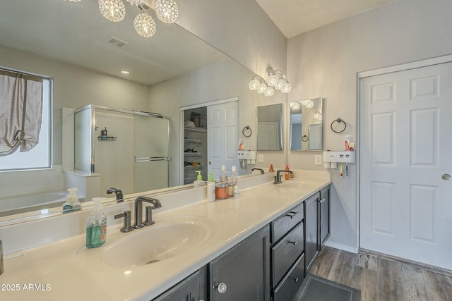 bathroom with visible vents, a stall shower, wood finished floors, and a sink