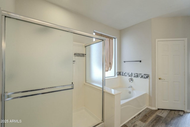 bathroom with a bath, a stall shower, and wood finished floors