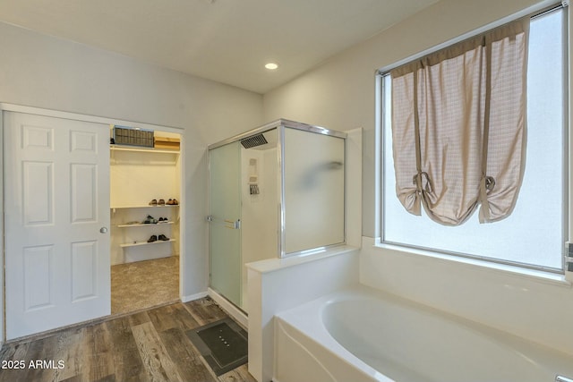 full bathroom with wood finished floors, a garden tub, and a stall shower