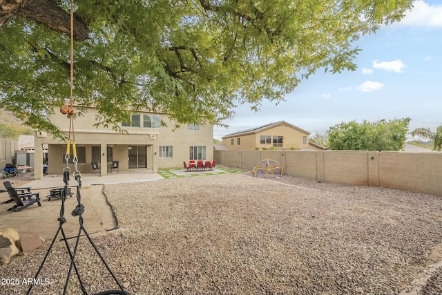 rear view of house featuring a fenced backyard, stucco siding, and a patio