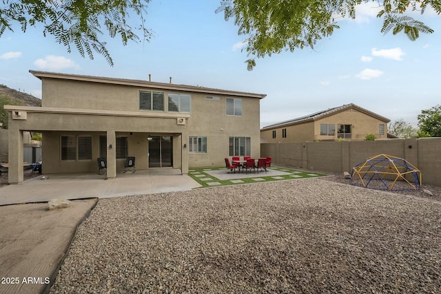 rear view of property featuring a fenced backyard, stucco siding, and a patio