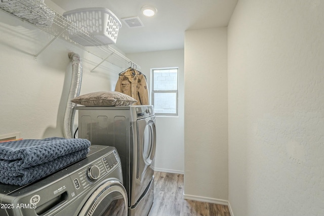 laundry area featuring wood finished floors, visible vents, baseboards, laundry area, and washer and dryer