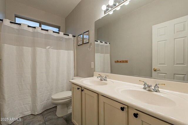 bathroom with tile patterned flooring, double vanity, toilet, and a sink