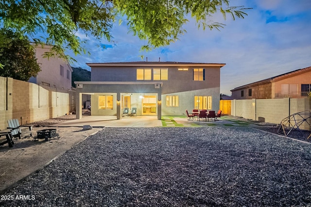 rear view of property with a patio, stucco siding, a fenced backyard, and an outdoor fire pit