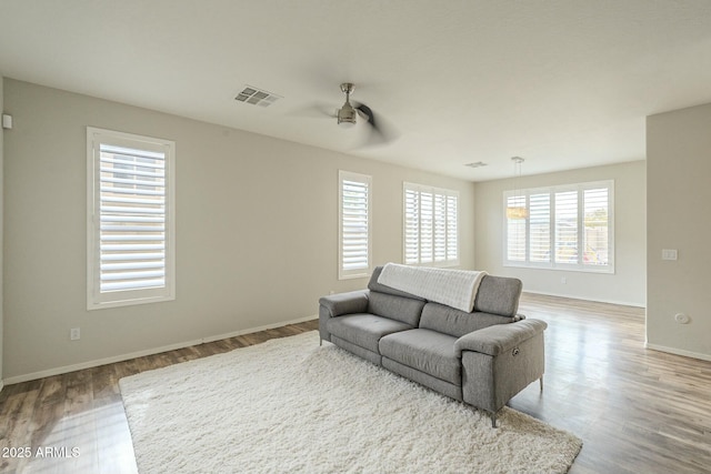 living area featuring ceiling fan, wood finished floors, visible vents, and baseboards