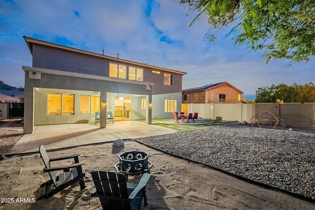 rear view of house with stucco siding, a fenced backyard, and a patio area