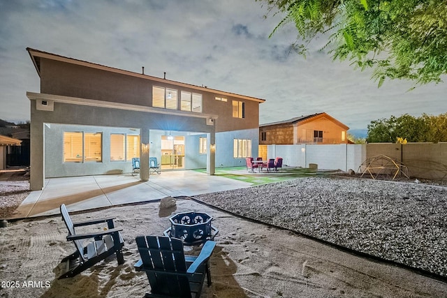 rear view of house featuring a patio area, fence, and stucco siding