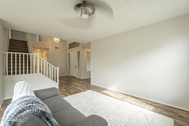 living room with ceiling fan, baseboards, wood finished floors, and stairs