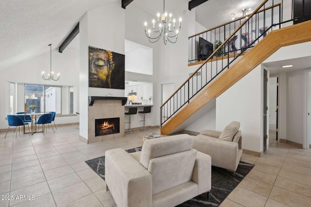 living room featuring beam ceiling, a tiled fireplace, light tile patterned floors, and a chandelier