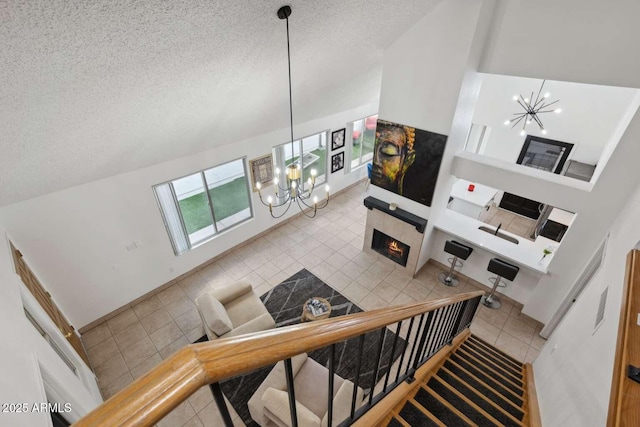 stairs with tile patterned floors, a textured ceiling, a notable chandelier, and a fireplace