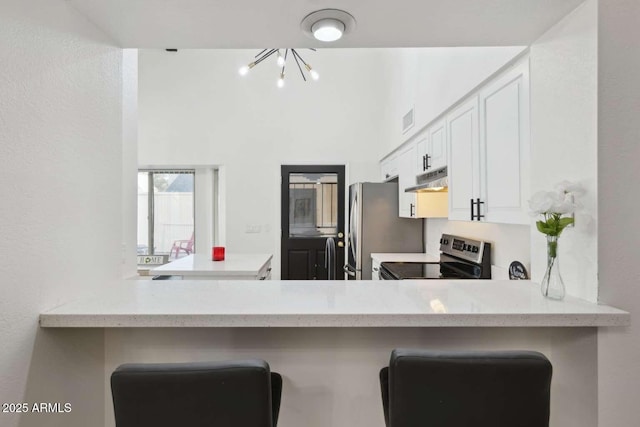 kitchen featuring a breakfast bar area, stainless steel appliances, kitchen peninsula, and white cabinets