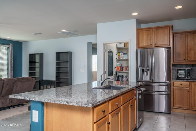 kitchen featuring visible vents, appliances with stainless steel finishes, a sink, light tile patterned floors, and open floor plan