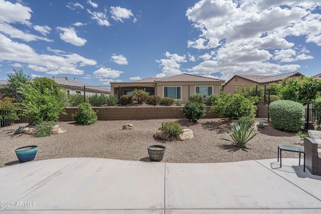 view of front of home with a patio area, fence, and a tiled roof