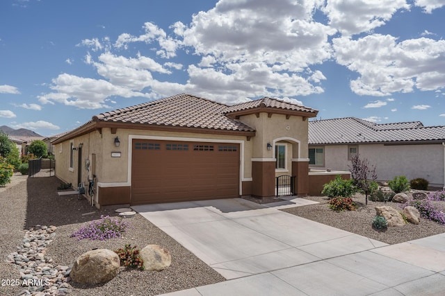 mediterranean / spanish house featuring a tiled roof, driveway, a gate, a garage, and stucco siding