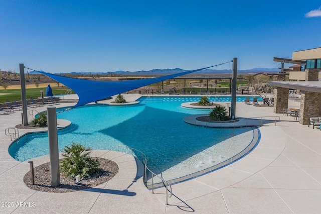 community pool with a mountain view and a patio area