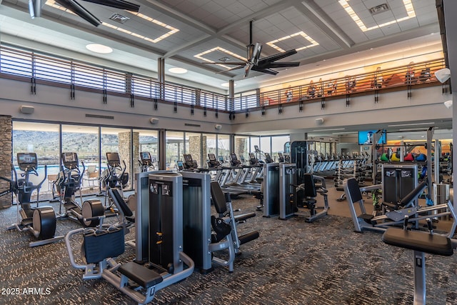 workout area featuring ceiling fan, visible vents, plenty of natural light, and a towering ceiling