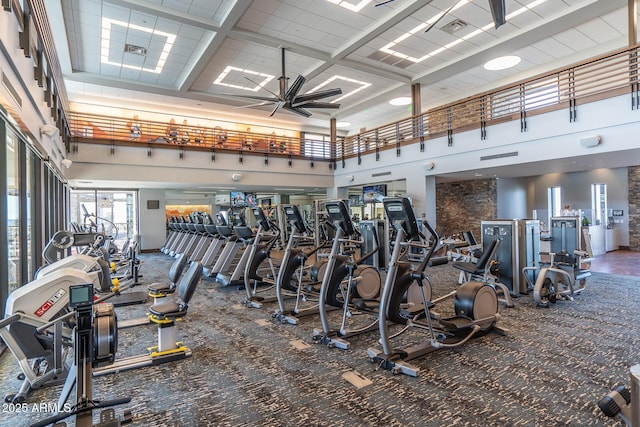 exercise room featuring a ceiling fan, visible vents, and a towering ceiling