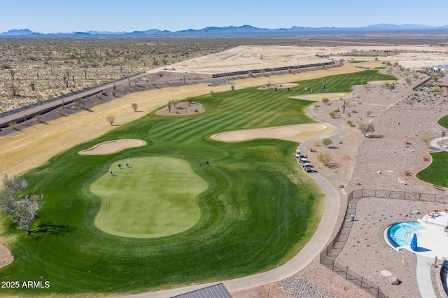 birds eye view of property featuring view of golf course, a mountain view, and view of desert