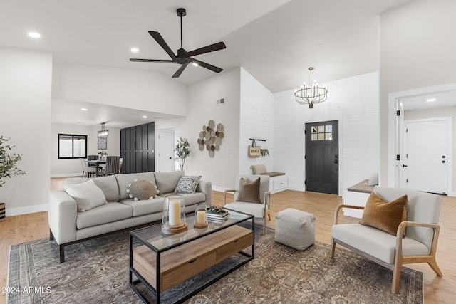 living room featuring ceiling fan with notable chandelier, hardwood / wood-style flooring, and high vaulted ceiling