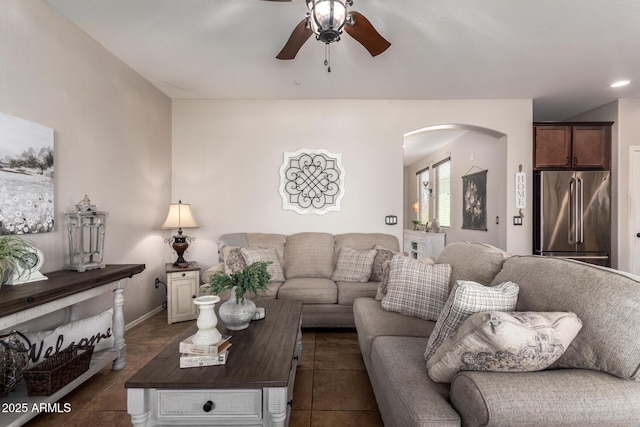 living room featuring ceiling fan, arched walkways, and dark tile patterned flooring