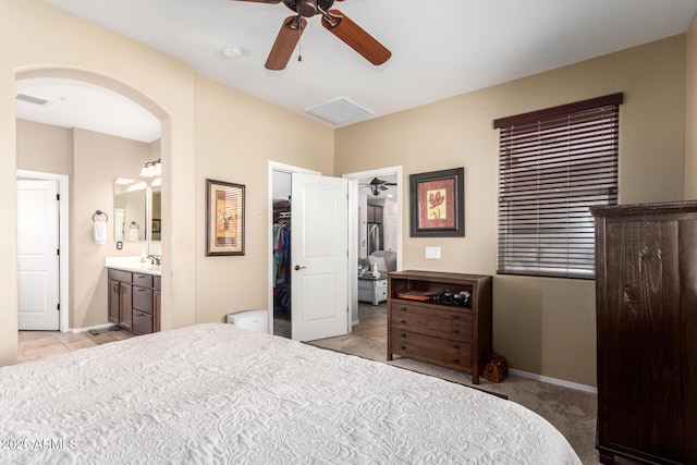 bedroom with ensuite bath, baseboards, arched walkways, and a closet