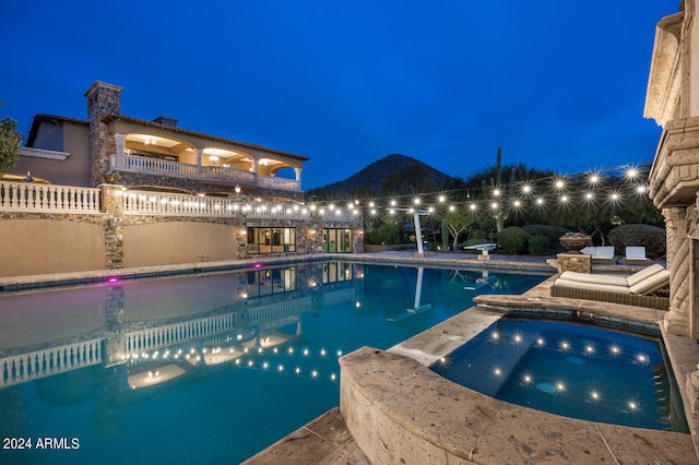 pool at night with an in ground hot tub and a patio