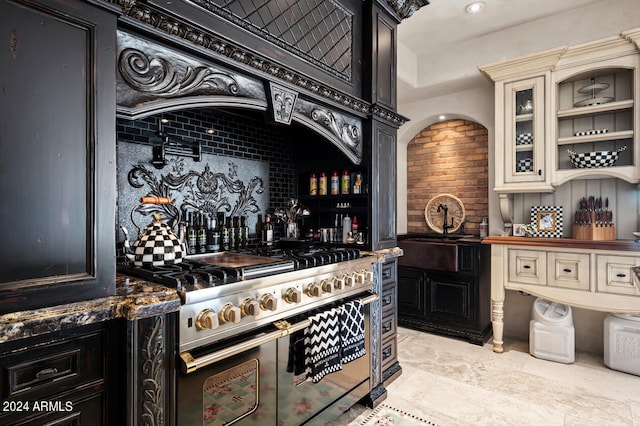 interior space featuring dark stone counters, double oven range, cream cabinets, and decorative backsplash