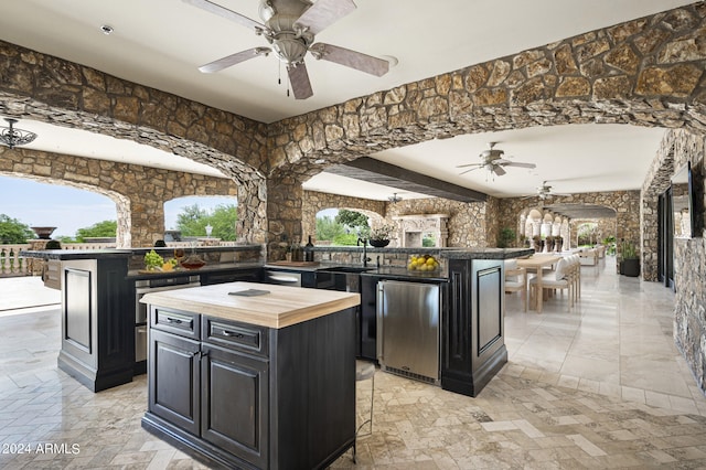 kitchen with wooden counters, a wealth of natural light, a kitchen island, and ceiling fan