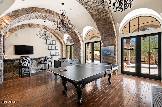 recreation room with a towering ceiling, french doors, a notable chandelier, and dark hardwood / wood-style floors