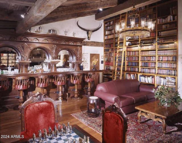 living room with built in features, hardwood / wood-style floors, and lofted ceiling with beams