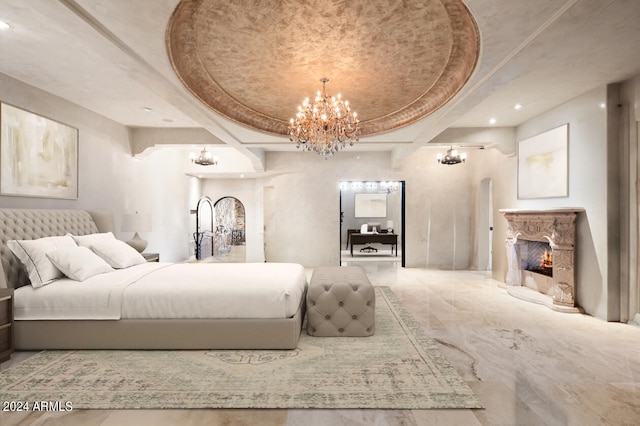 bedroom with coffered ceiling, a raised ceiling, a notable chandelier, and a premium fireplace