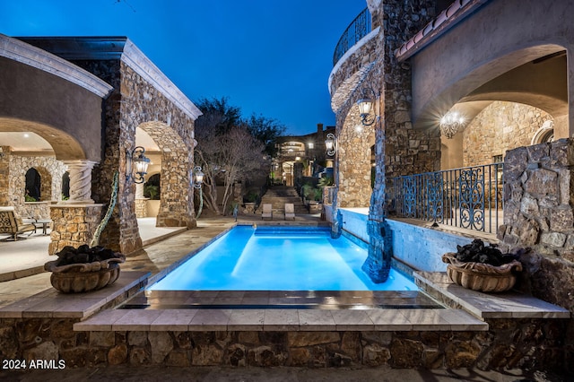 pool at night featuring a patio