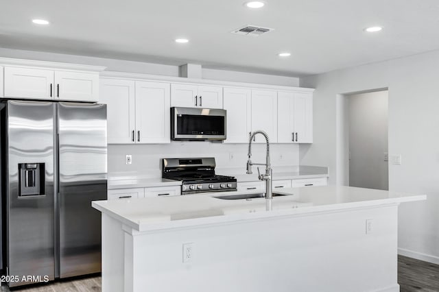 kitchen with appliances with stainless steel finishes, a kitchen island with sink, and white cabinets