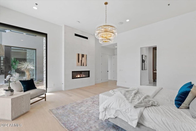 bedroom with a chandelier, light wood-type flooring, and a fireplace